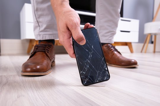 Man Picking Up Damaged Mobile Phone