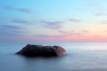 A stone in a calm sea at sunset - Powered by Adobe