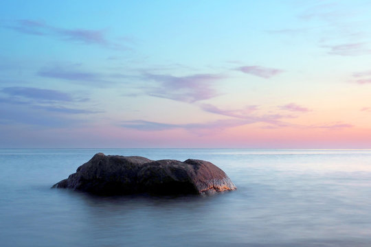 A stone in a calm sea at sunset