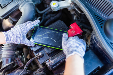 Close-up of mechanic's hand in gloves with digital tablet, car in background. Tablet for diagnosis...