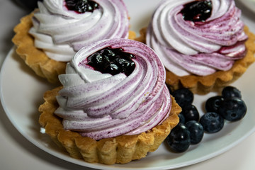 Sweet tartlet with meringue and huckleberry jam and bouquet of phlox on white background closeup