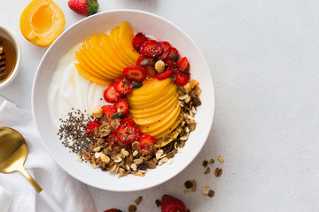 Healthy breakfast. Greek yogurt with fresh apricots, strawberries, walnuts, muesli and honey. Top view