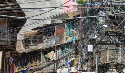 CLOSE UP: Wiring gets chaotically tangled up on the side of apartment building.