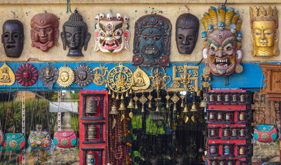 Naklejka premium CLOSE UP: Traditional wooden buddhist masks hang on the wall of a souvenir shop.