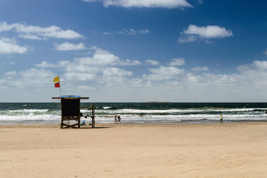 La playa con torre de guardavidas y turistas caminando