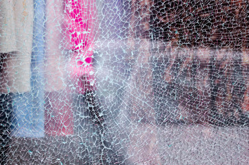 Broken glass of a shop window of a clothing store with unfocused background