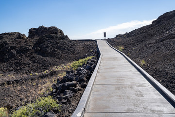 The Snow Cone trail, a paved walkway leading to a cinder cone with year-round snow, in Craters of the Moon National Monument in Idaho