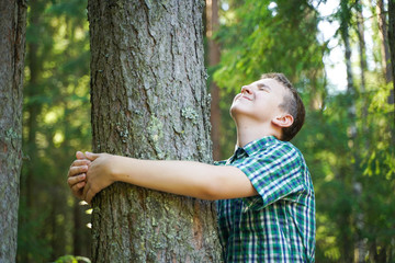 teenager boy hug and love big tree in the forest alone in summer day