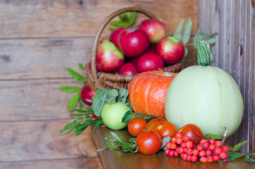 basket with fruits on a wooden background. harvesting autumn and summer harvest. vegetables and fruits pumpkin, zucchini, apple, rowan, pea, cherry. soft focus. copy space.