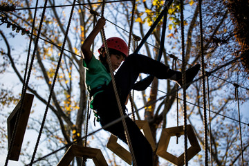 a young boy with helmet and protective equipment at adventure or training park or zipline