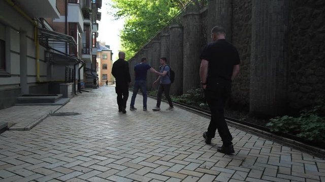 Young lonely male walking down alleyway fighting off muggers applying Krav Maga self defense techniques and running away. Group of robbers attacking man