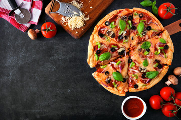 Homemade pizza with pepperoni, mushrooms, green peppers, olives, onions and basil. Top view, corner...