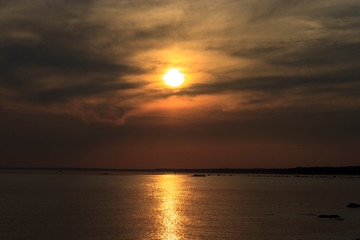 Scenic sunset over the sea. Reflection of the sun in water. The sky is painted with bright colors. Sunset beach in a summer evening. Gulf of Finland, Baltic sea,  Komarovo, Saint-Petersburg, Russia.