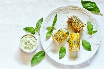 grilled corn on a skewer with basil butter. top view. place for text. copy space