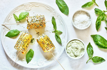 grilled corn on a skewer with basil butter. top view.