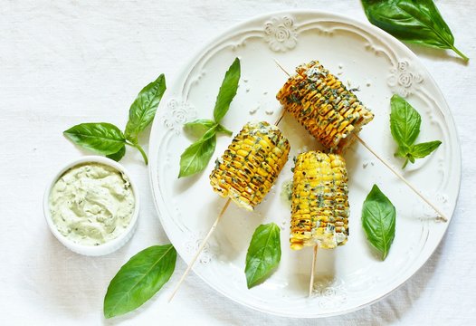 grilled corn on a skewer with basil butter. top view.