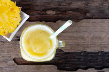 Pineapple smoothie yellow fruit juice healthy drink delicious in a glass morning drink on a wooden background from the top view.