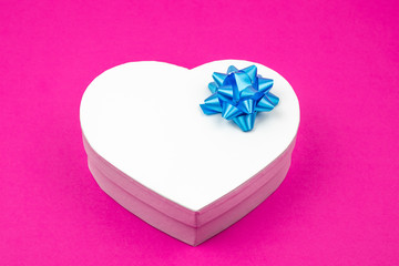 Heart shaped gift box with blue bow on a pink background. Mock up. Empty place for an inscription. Present for the christmas, thanks giving day, birthday holiday. 