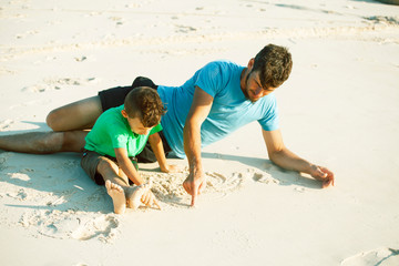 Fototapeta premium happy family on beach playing, father with son walking sea coast, rocks behind smiling taking vacation