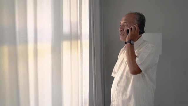 portrait of oldman standing and make a call by smartphone to contact her wife