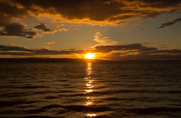 Fototapeta premium sunset, dramatic clouds, reflection of the sun in the water of the lake