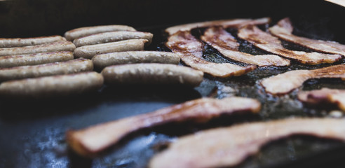 Bacon and Sausage cooking on a camp grill
