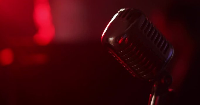 Music concert in nightclub. Closeup microphone on stage against auditorium background on illumination blue lights. Waiting a singer in light of spotlight.