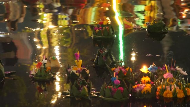 Paper lotus flower with candle floating on a river at night in Loy krathong festival, traditional Siamese new year festival celebrated in Thailand.