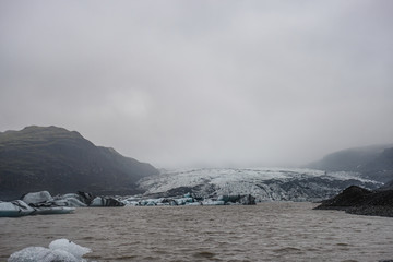 The Solheimajokull Glacier in Iceland showing icebergs and calved ice in the lagoon as ice calves...
