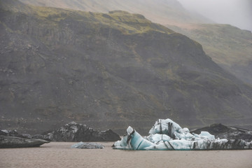 The Solheimajokull Glacier in Iceland showing icebergs and calved ice in the lagoon as ice calves...