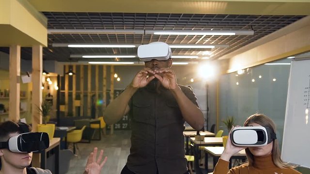 Young concentrated man in virtual reality VR glasses working in the office.