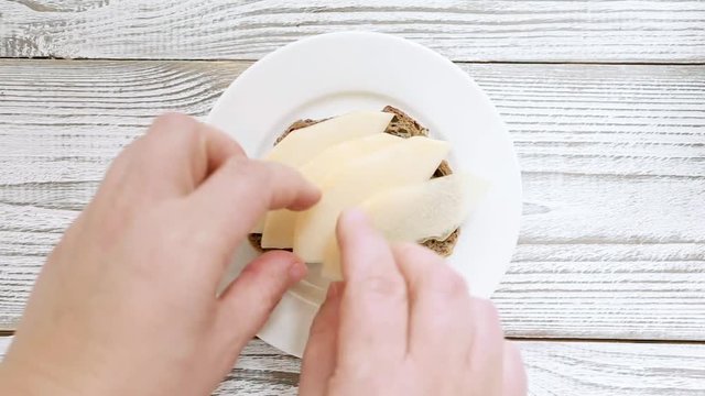 Chef hand making sandwich with pear, dorblu cheese, honey and nuts for breakfast and lunch. Top view, close up