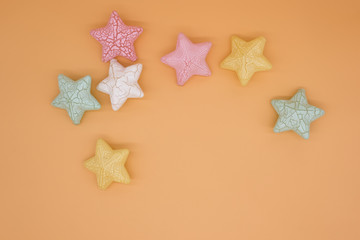 Fototapeta na wymiar Beautiful colorful stars props placed on orange background creative top view, christmas decoration background