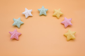 Beautiful colorful stars props neatly circled on orange background creative top view, christmas decoration background