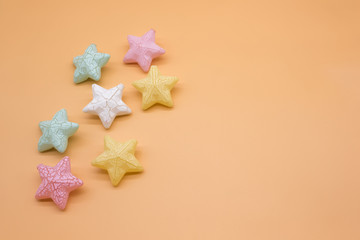 Beautiful colorful stars props placed on orange background creative top view, christmas decoration...