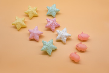 Fototapeta na wymiar Colorful five-pointed star and three toy pig props composing creative holiday drawing top view
