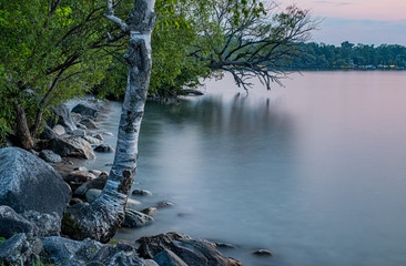 sunset at Franklin Beach Georgina Ontario Canada with nice trees, rocks, lake view, clouds, sun and wooden path
