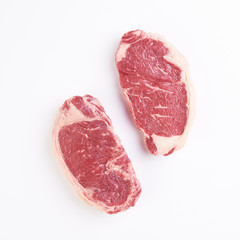 Two striploine steak uncooked on white background with copyspace around