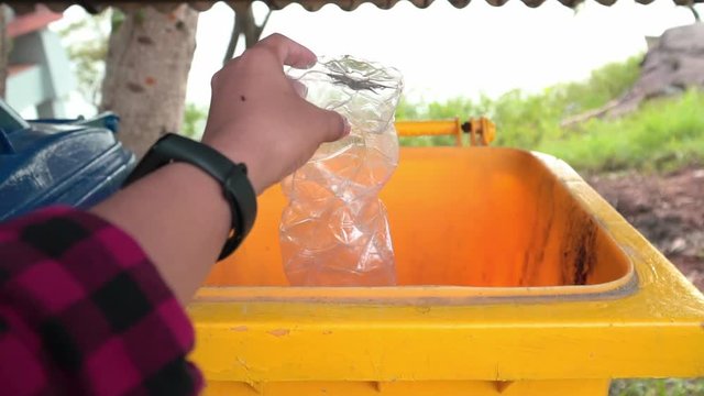 Hand picking up a bottle plastic in to a bin , protect environment from a pollution concept.