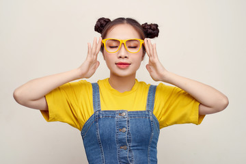 Beautiful Asian woman has two buns of hair wearing a jeans dungaree and adjusting glasses