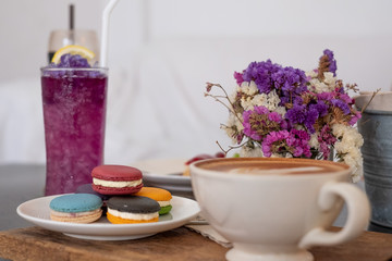 Butterfly pea water and macaron and hot coffee mug in the front