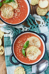 Traditional gazpacho Soup in two plates on a green napkin decorated with Basil and crackers top view close-up