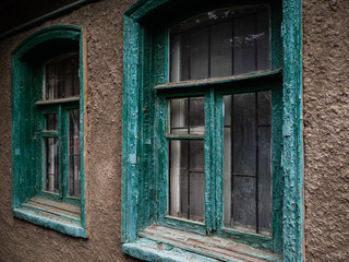 Green wooden windows on the gray house. Gloomy view of the house