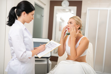 Obraz na płótnie Canvas Woman telling a beauty doctor about needed procedures.