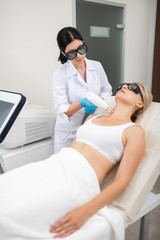 Beauty doctor giving her patient laser neck skin treatment.