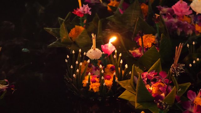 Paper lotus flower with candle floating on a river at night in Loy krathong festival, traditional Siamese new year festival celebrated in Thailand.