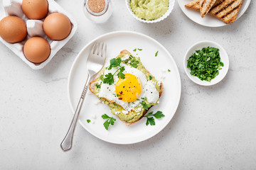 Toast with avocado puree and fried egg, healthy breakfast. 