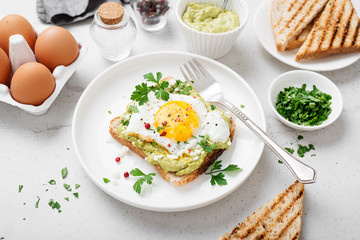Toast with avocado puree and fried egg, healthy breakfast. 