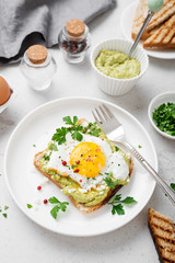 Toast with avocado puree and fried egg, healthy breakfast. 