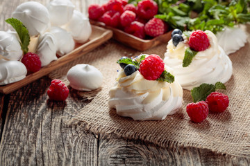 Dessert Pavlova with raspberries, blueberries and mint on a old wooden table.